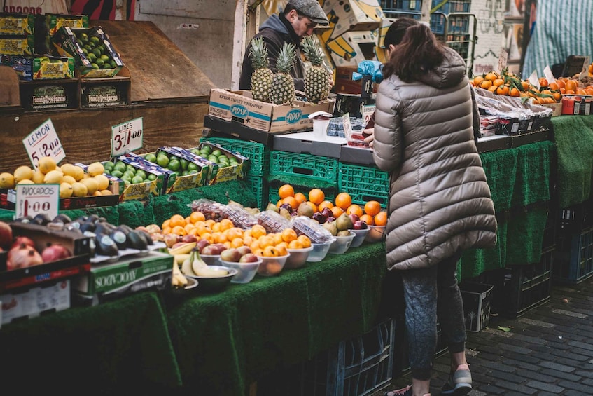 A fruit market with various fruits and vegetables on display, including avocados, lemons, limes, and oranges. 2