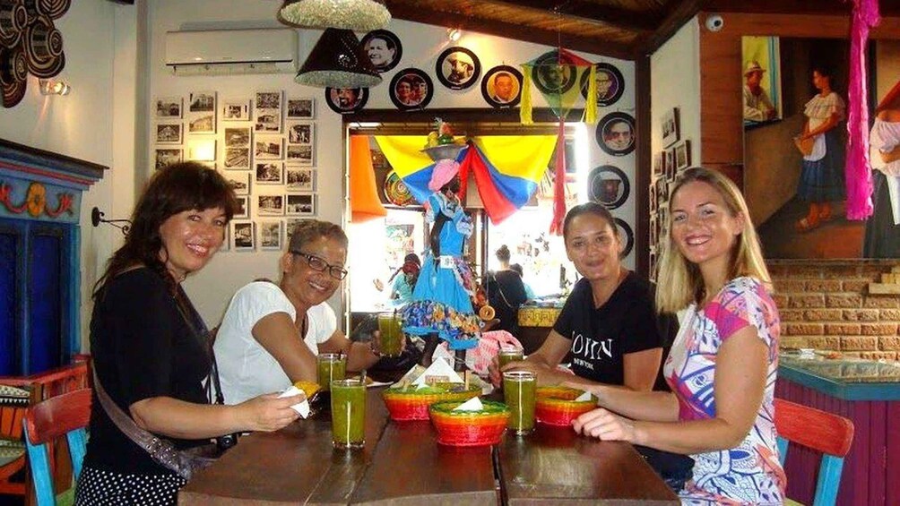 A group of people sitting around a table with colorful drinks and a festive atmosphere. 2
