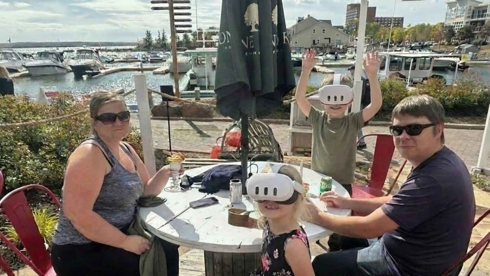 A group of people at a waterfront café with a view of boats and a building in the background. 3