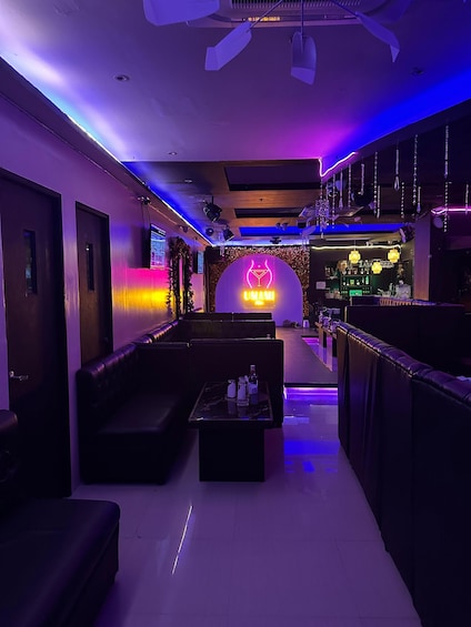 A bar with a neon sign, leather seating, and a bar counter. 3
