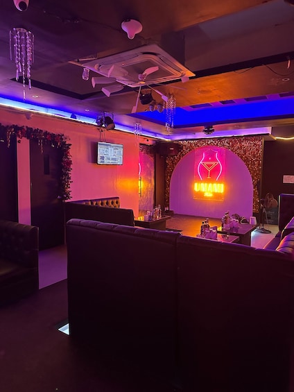 A bar with a neon sign reading 'UMAMI Bar' and a stage with a cocktail glass logo. 2