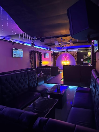 A dimly lit lounge with plush seating and a neon sign. 4