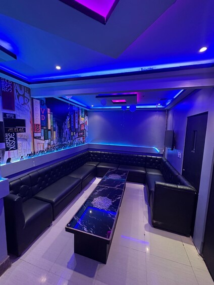 A modern lounge with a black leather sofa, a marble coffee table, and a wall adorned with various signs. 1