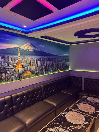 A room with a mural of a cityscape and a mountain, black leather seating, and a table with a geometric pattern. 5