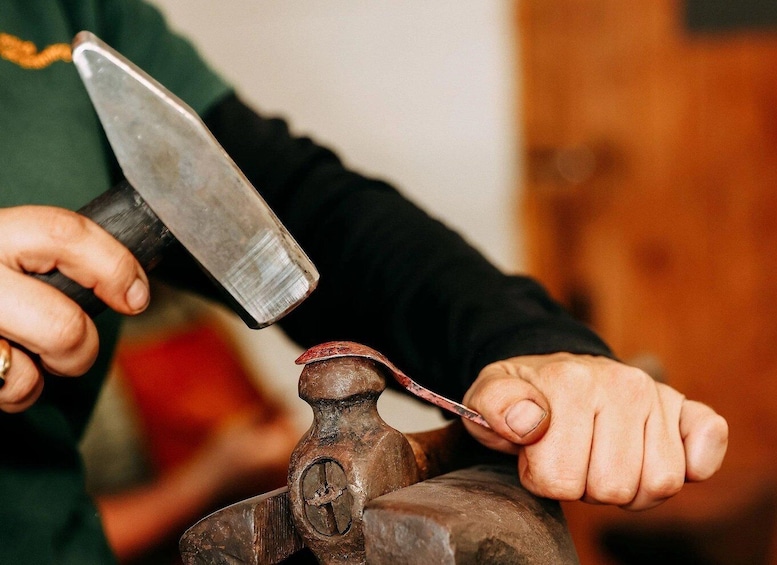 A person using a hammer to shape metal on an anvil. 2
