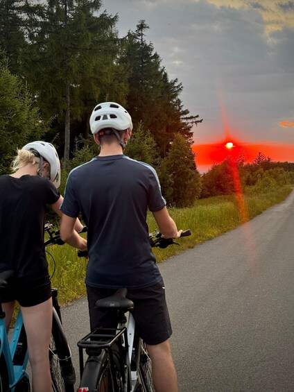 Two cyclists on a road with a sunset in the background. 3