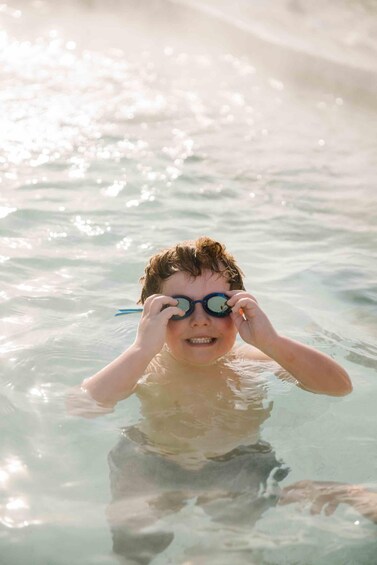 A person in clear water, wearing a yellow swimsuit, with sunlight reflecting off the surface. 4