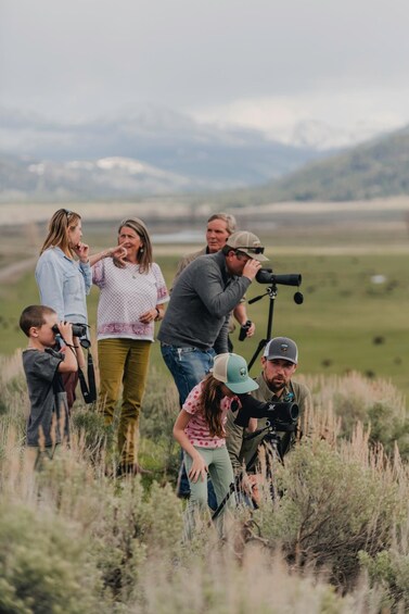 A group of people in a field with a camera on a tripod. 2
