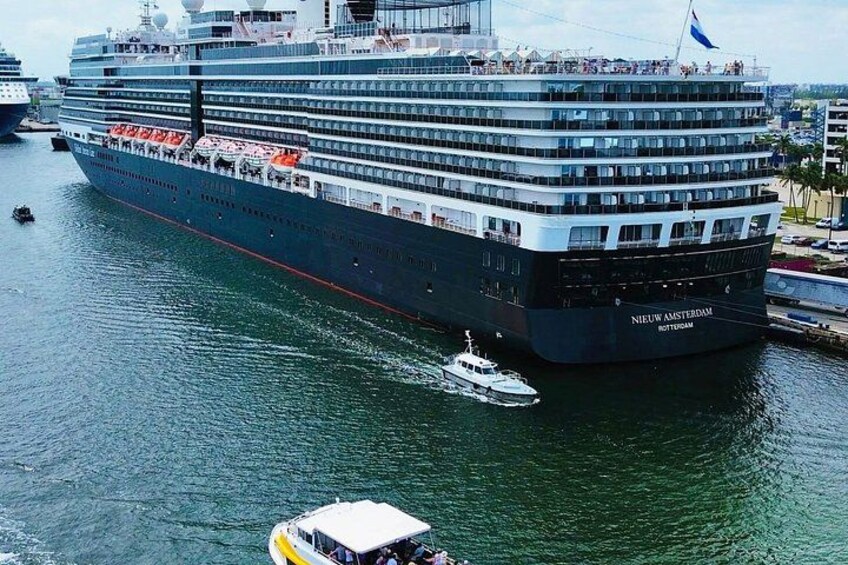 A large cruise ship docked at a port with a smaller boat nearby. 2