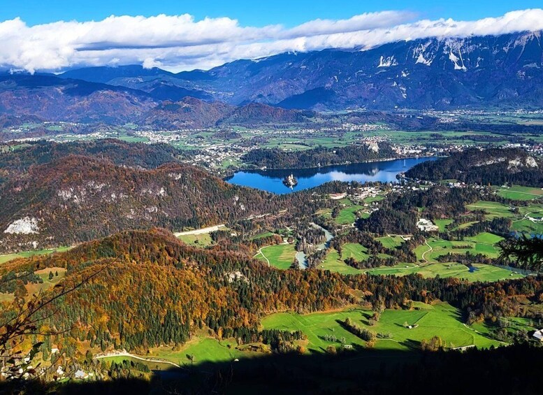 A mountainous landscape with a lake, green fields, and a town. 1