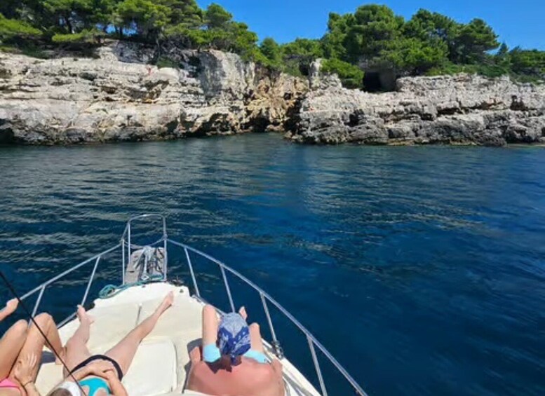 A boat on a calm sea with rocky cliffs and trees in the background. 2