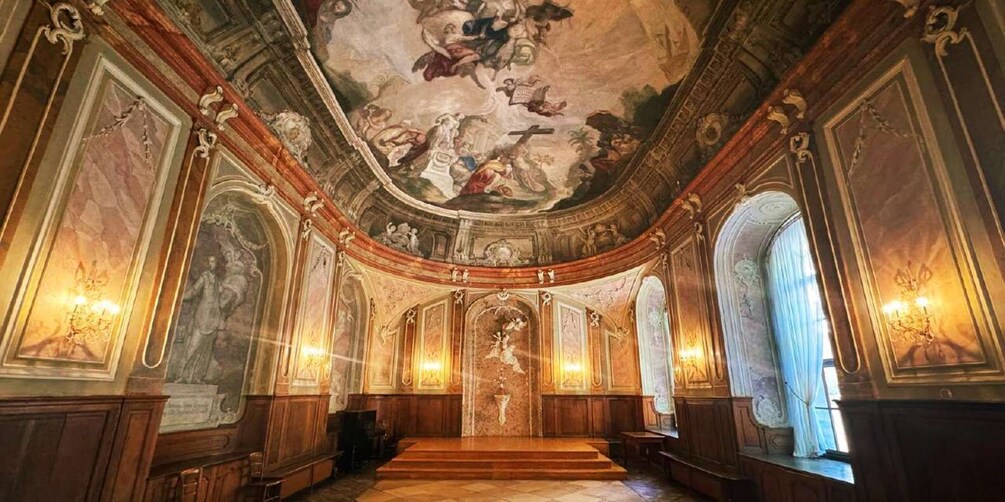 An ornate interior with a high ceiling, frescoes, and classical architecture. 2