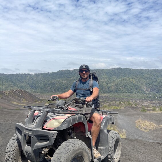 A person riding an ATV on a dirt path with a mountainous landscape in the background. 5