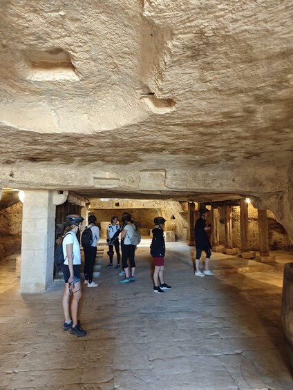 A group of people inside a cave with stone walls and a stone floor. 3