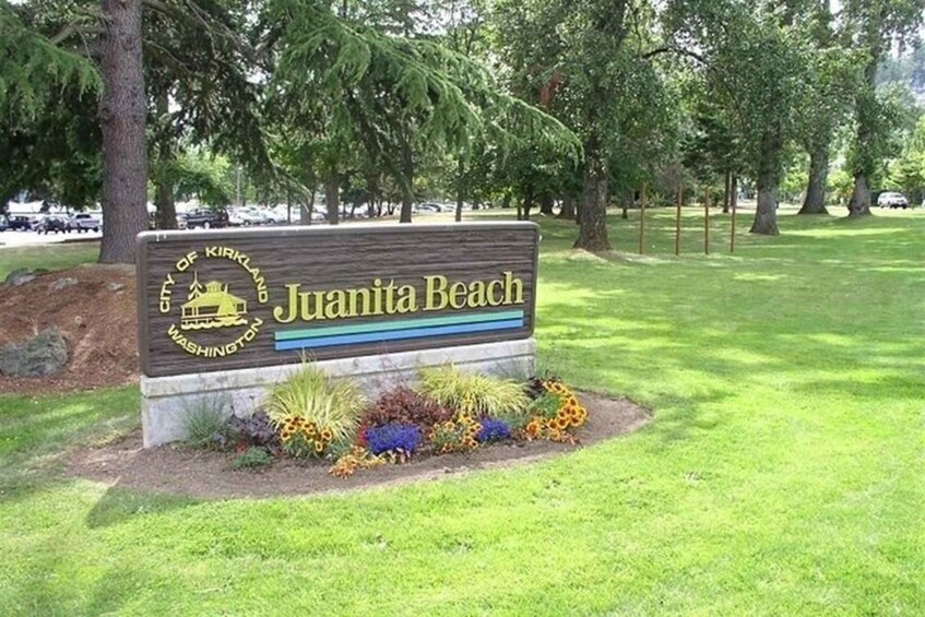 A sign for Juanita Beach in the City of Kirkland, Washington, surrounded by grass and trees. 2