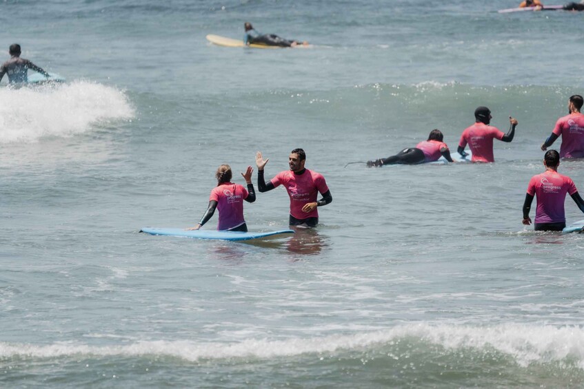 People in pink wetsuits on surfboards in the ocean. 2