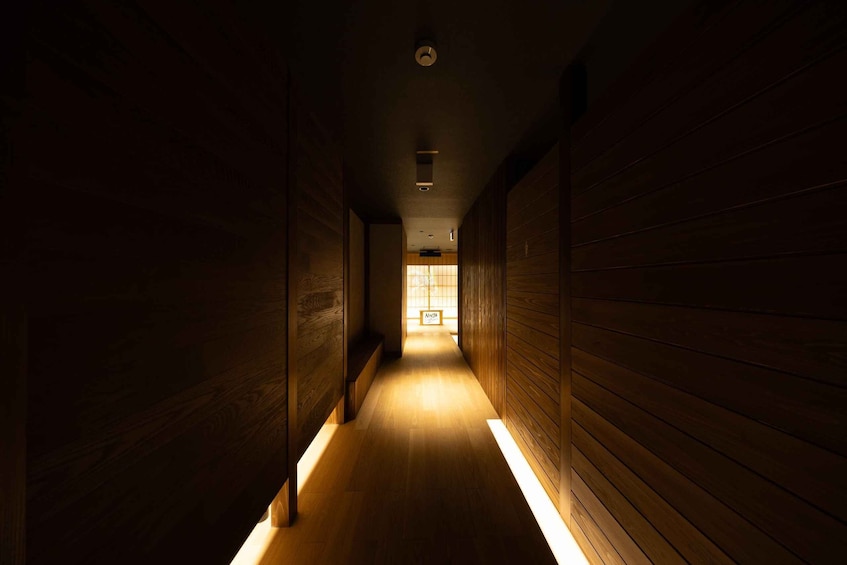 A dimly lit wooden hallway with a light source at the end. 4