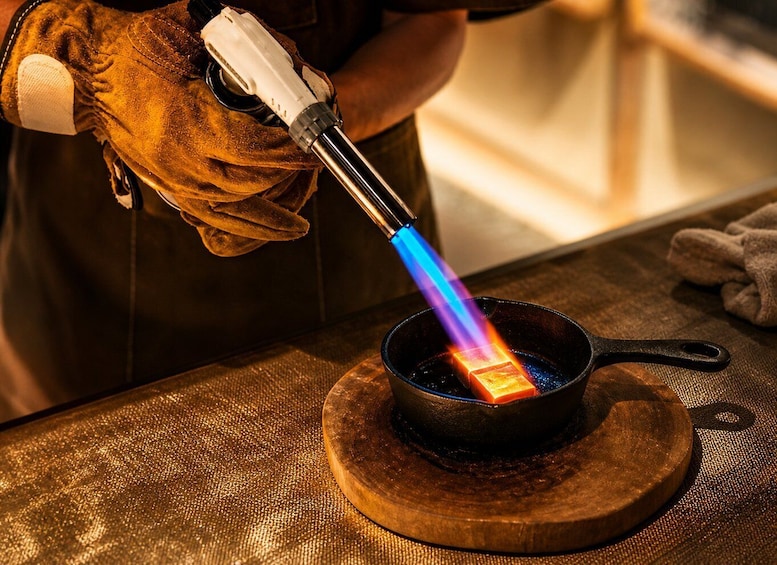 A person using a blowtorch to heat a metal object in a pan. 5