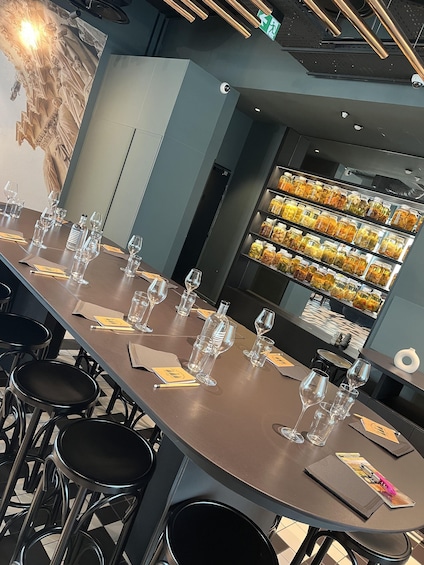 A bar with a long counter, glasses, and a display of preserved fruits. 5
