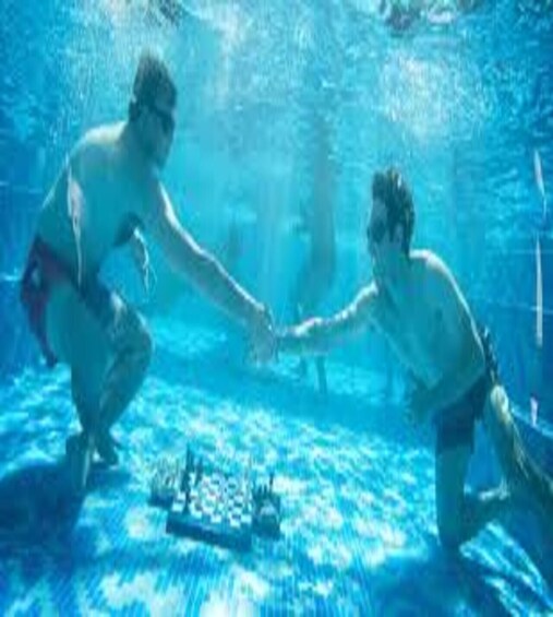 Two people underwater in a pool, holding hands. 2