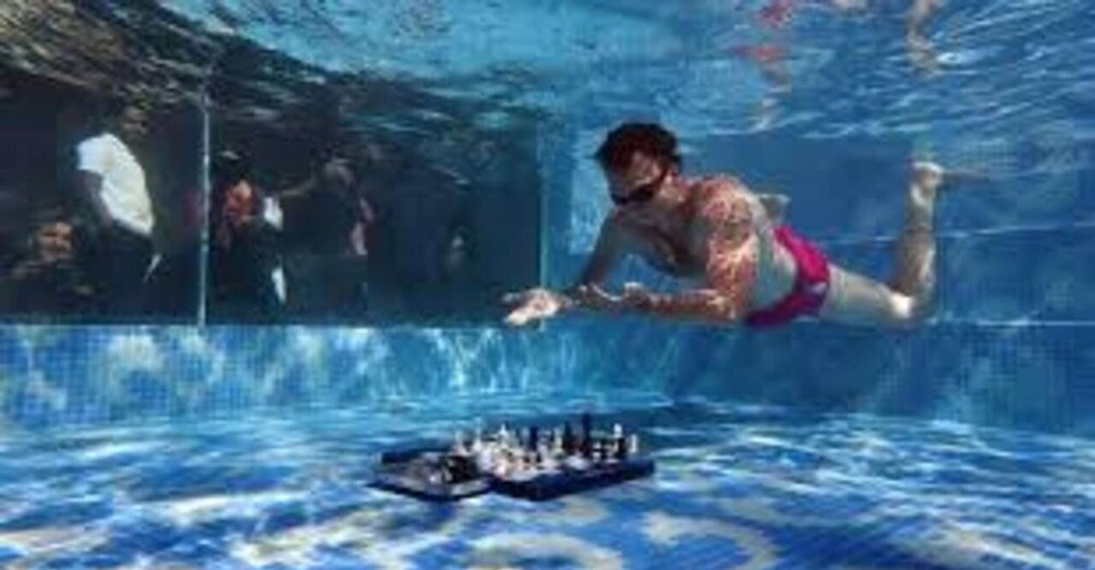 A person swimming underwater in a pool. 3