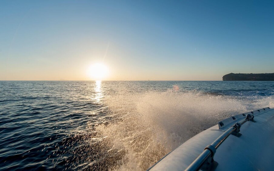 A boat's wake in the ocean with the sun setting in the background. 2