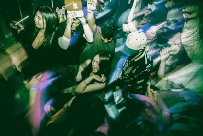 A crowded indoor event with people holding drinks and engaging in social activities. 3
