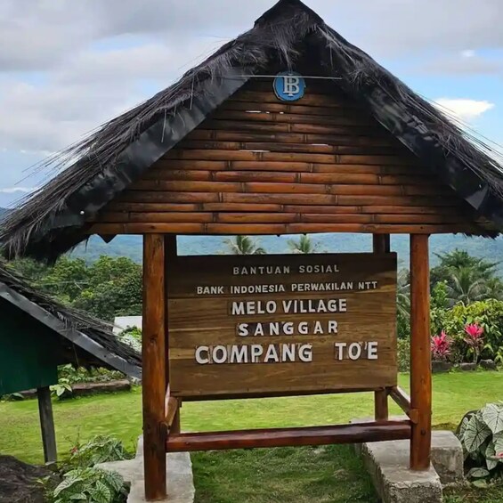 A wooden sign with text indicating a location in Molo Village, Sanggar, and a bank named Bank Indonesia. 5