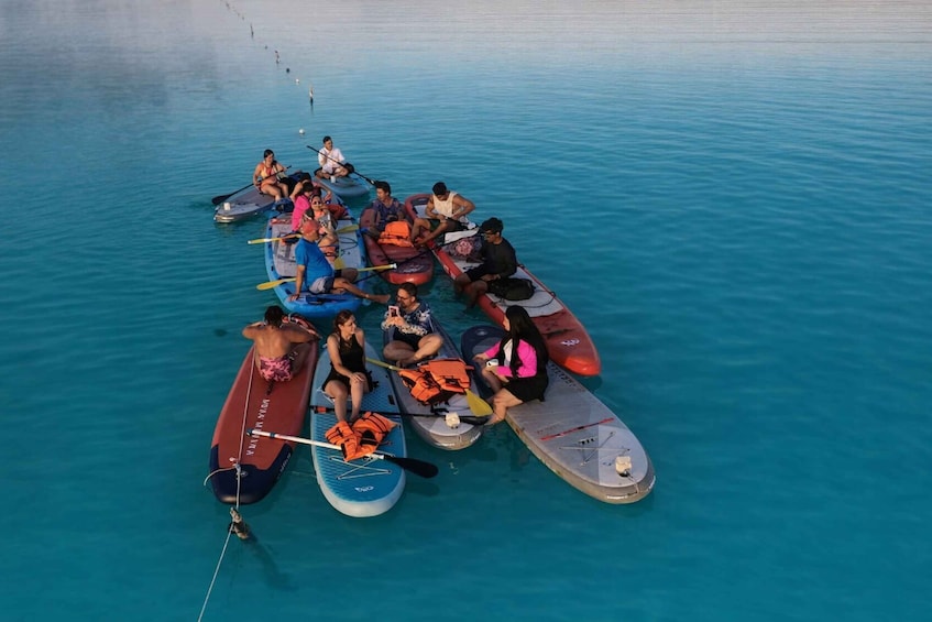A group of people on paddleboards in a calm body of water. 3