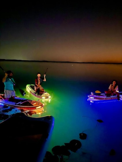 A nighttime scene with illuminated boats on a calm body of water. 2