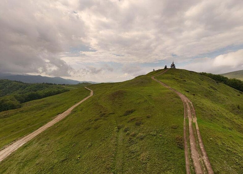A grassy hill with a dirt path leading to a small structure. 2