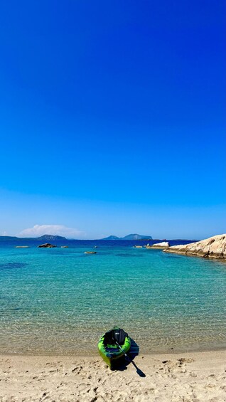 A clear blue sea with a green inflatable boat on the sandy beach. 4