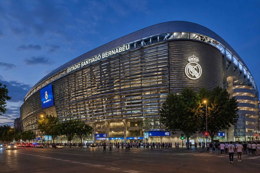A modern stadium with a curved facade and the name 'Estadio Santiago Bernabéu' prominently displayed. 1