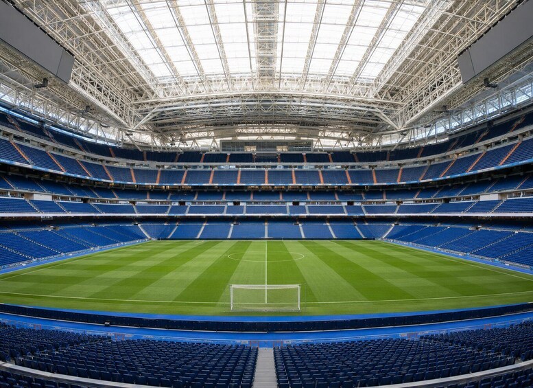 A large, empty stadium with a green field and blue seating. 2