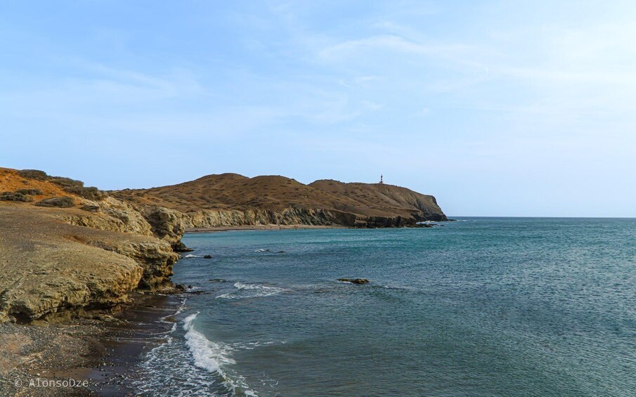 A coastal landscape with rocky cliffs, a lighthouse, and calm sea. 5
