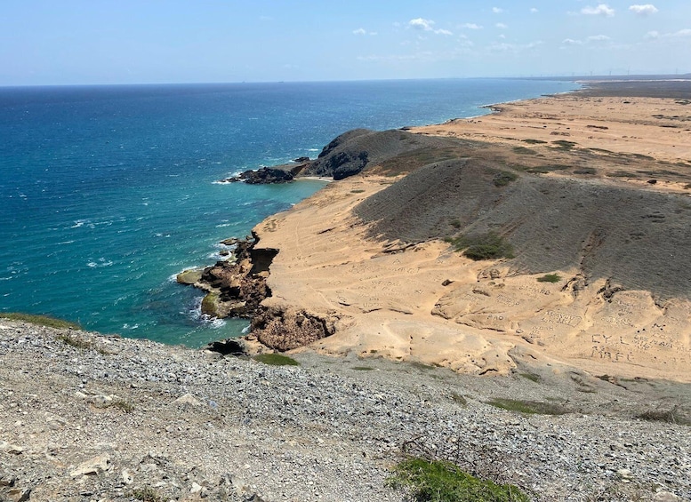 A coastal landscape with rocky cliffs, a sandy beach, and the ocean. 2
