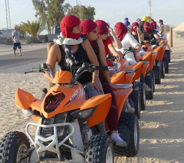A group of people on ATVs lined up on a sandy beach. 4
