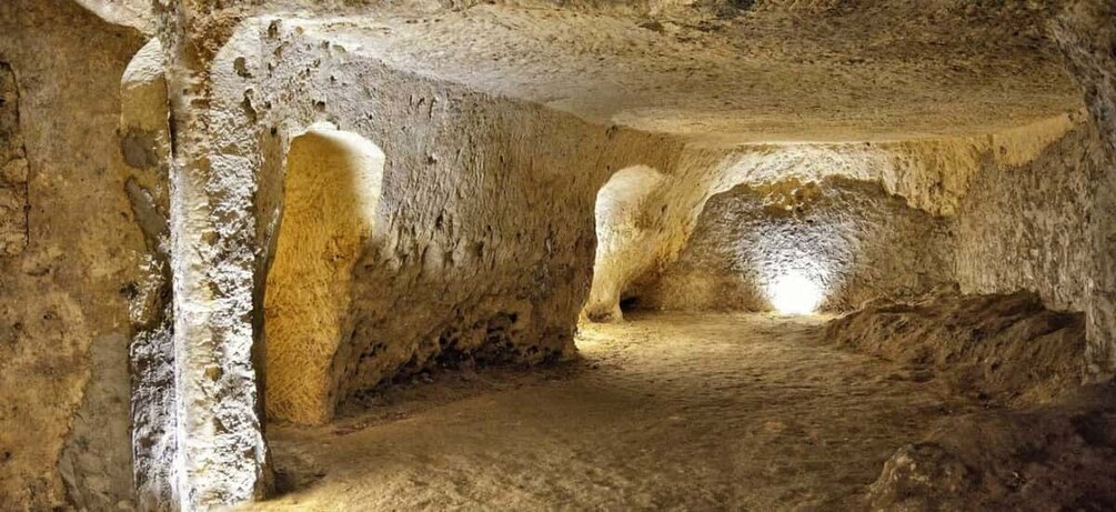 A cave interior with stalactites, a narrow passage, and a large rock formation. 3