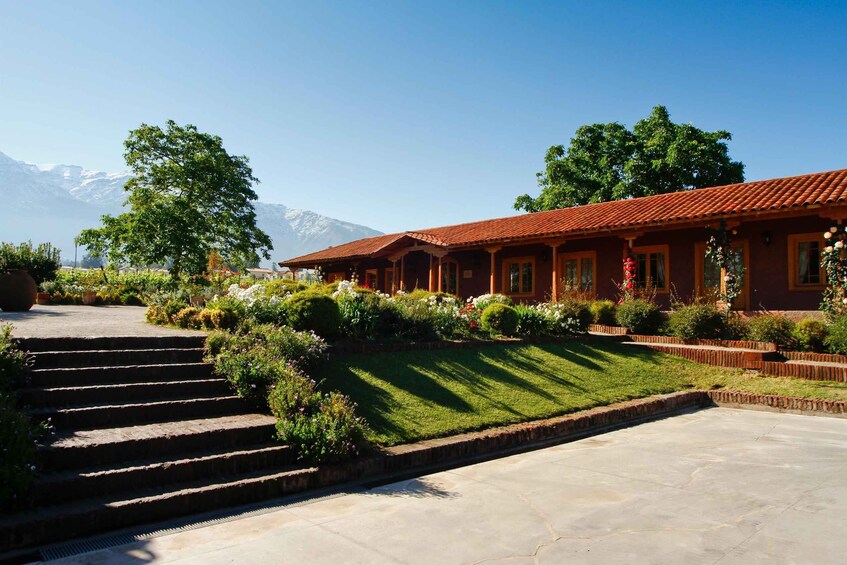 A red-roofed building with a garden and steps leading up to it, surrounded by mountains. 2