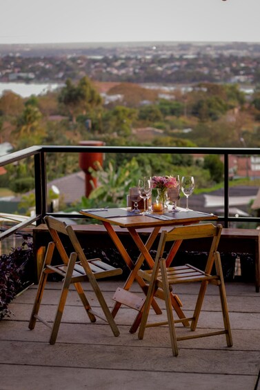 A wooden table with chairs set on a balcony overlooking a cityscape. 3
