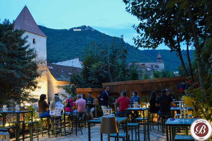An outdoor dining area with tables and chairs, surrounded by trees and a mountain in the background. 5