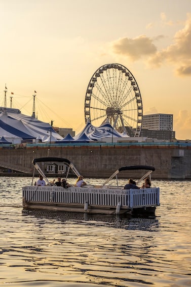 A boat with people on a body of water, a large Ferris wheel, and tents in the background. 2
