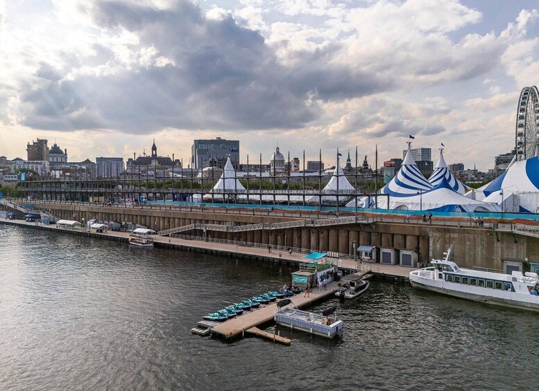 A waterfront with boats docked, a pier, and a cityscape with distinctive buildings and a Ferris wheel in the background. 5