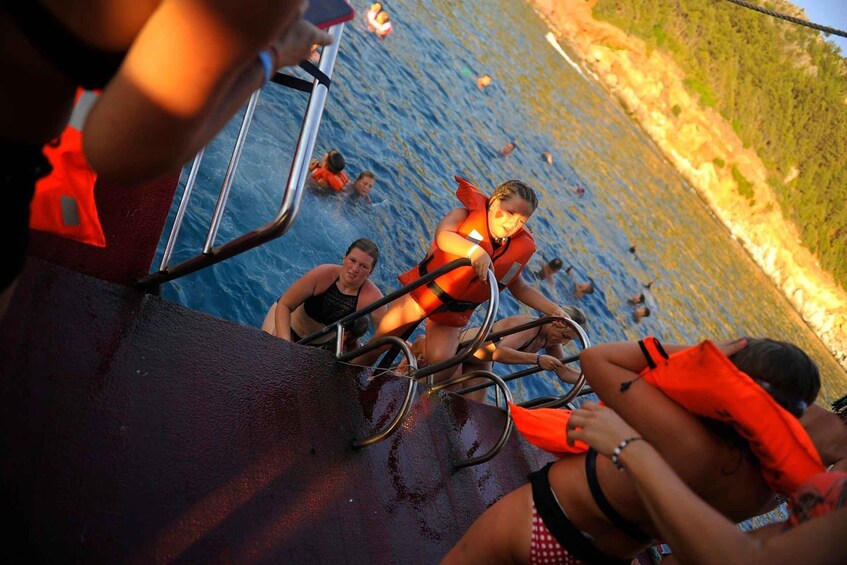 A boat with people wearing life jackets, a rocky shoreline, and a body of water. 4