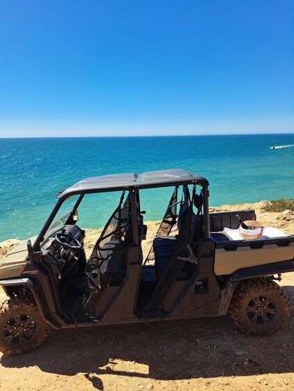 A CF MOTO EPS4X4 off-road vehicle parked on a sandy beach with the ocean in the background. 5