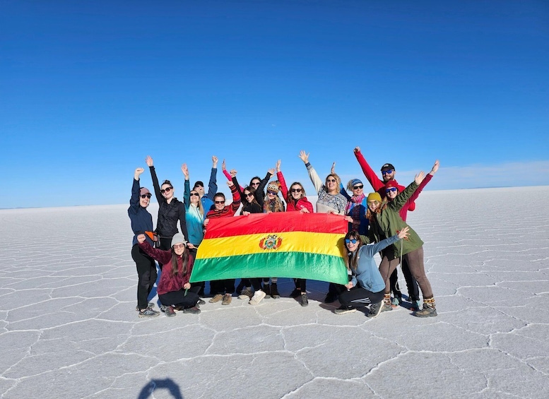 A group of people holding a flag in a vast, flat, salt flat landscape. 4