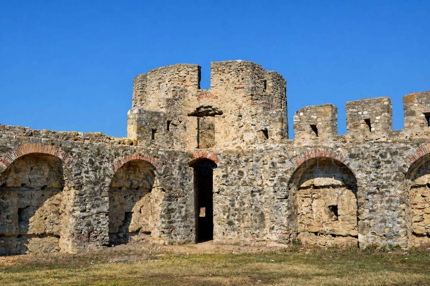 A historic stone fortress with arched openings and crenellated towers. 4