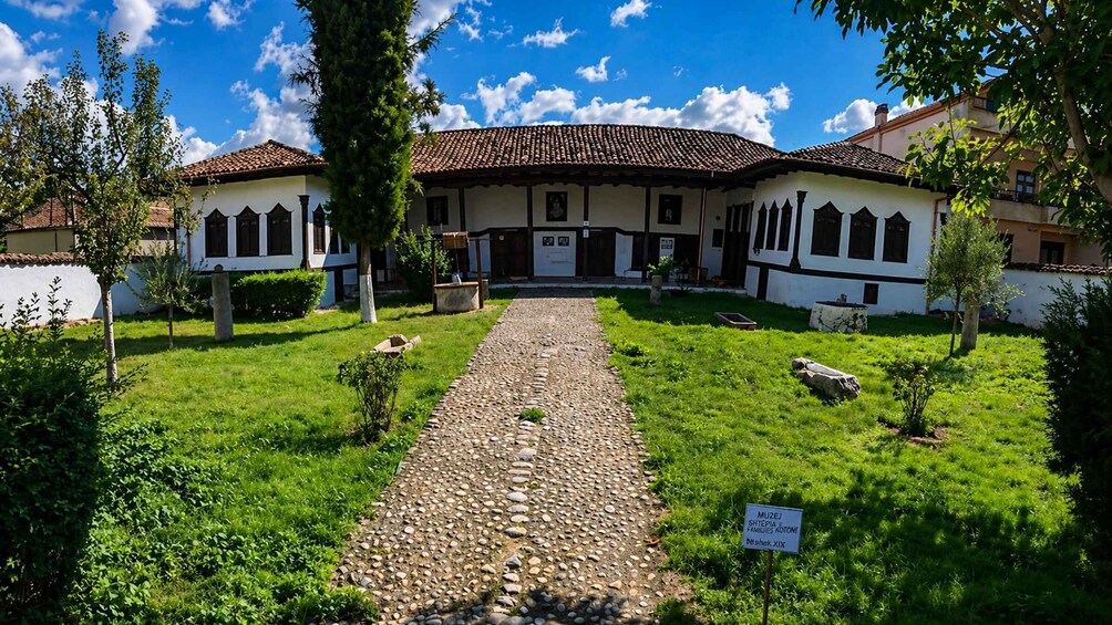 A traditional building with a tiled roof, surrounded by a well-maintained garden and a stone pathway leading to the entrance. 5