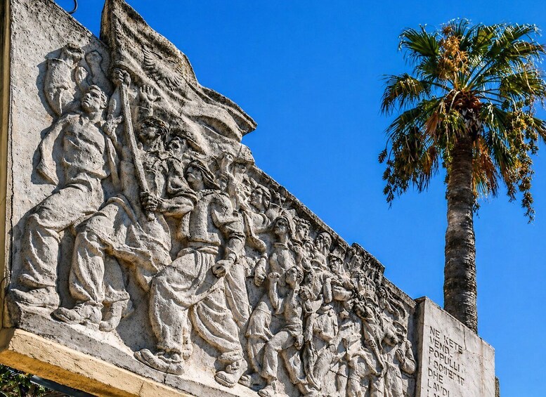 A detailed stone relief sculpture depicting a historical scene with multiple figures, including soldiers and a central figure holding a staff. 3