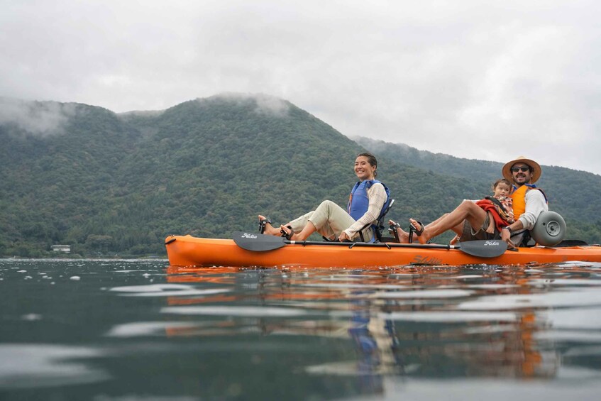 A person in a kayak on a body of water with mountains in the background. 1